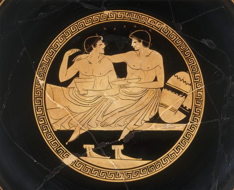 This image has been given the description of a '...courting couple at the symposium.' and a 'Symposium scene with youths.'. Interior of an Attic cup, around 500 - 450 BCE.