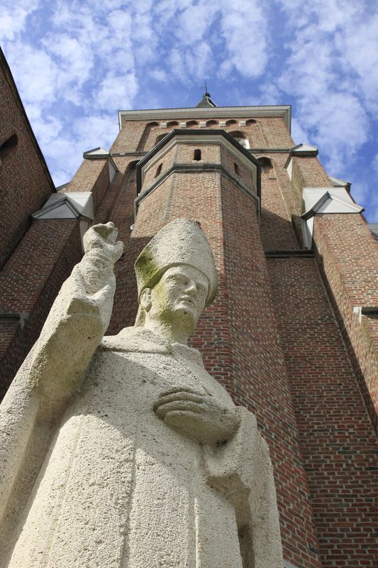 Stone statue of a priest or cardnial in front of a church, demonstrating the power and authority of the clergy.