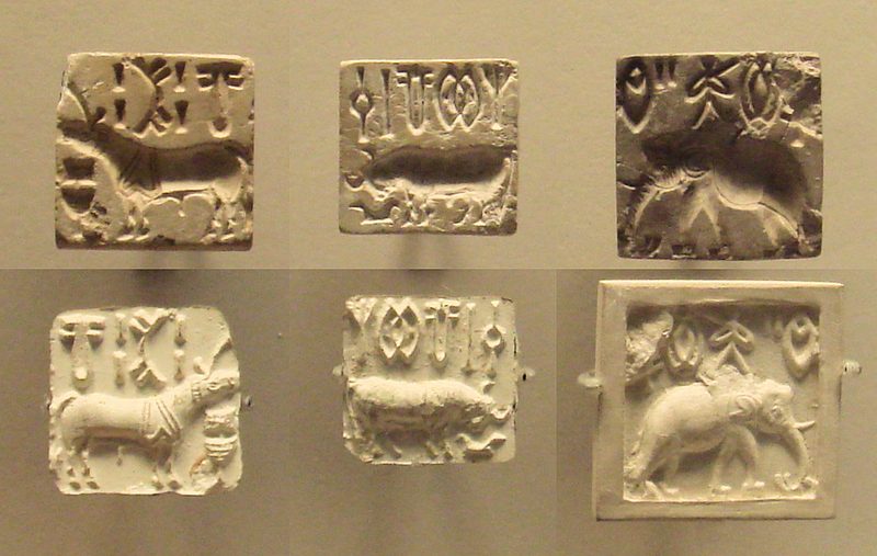 Three stamp seals and their impressions bearing Indus script characters alongside animals: 'unicorn' (left), bull (centre), and elephant (right).