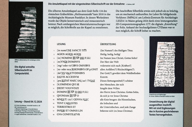Photograph of the info display of the amulet in the Archaeological Museum of the City of Frankfurt am Main, showing the text of the inscription.